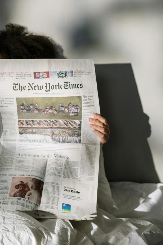 a person laying in bed reading a newspaper, a picture, trending on unsplash, in the cover of new york times, news broadcast, symmetrical image, tourist photo
