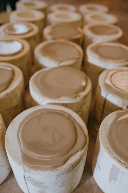 a group of clay pots sitting on top of a wooden table, inspired by Rachel Whiteread, unsplash, process art, beige, bottom body close up, coating a stubborn core.', cast in epoxy