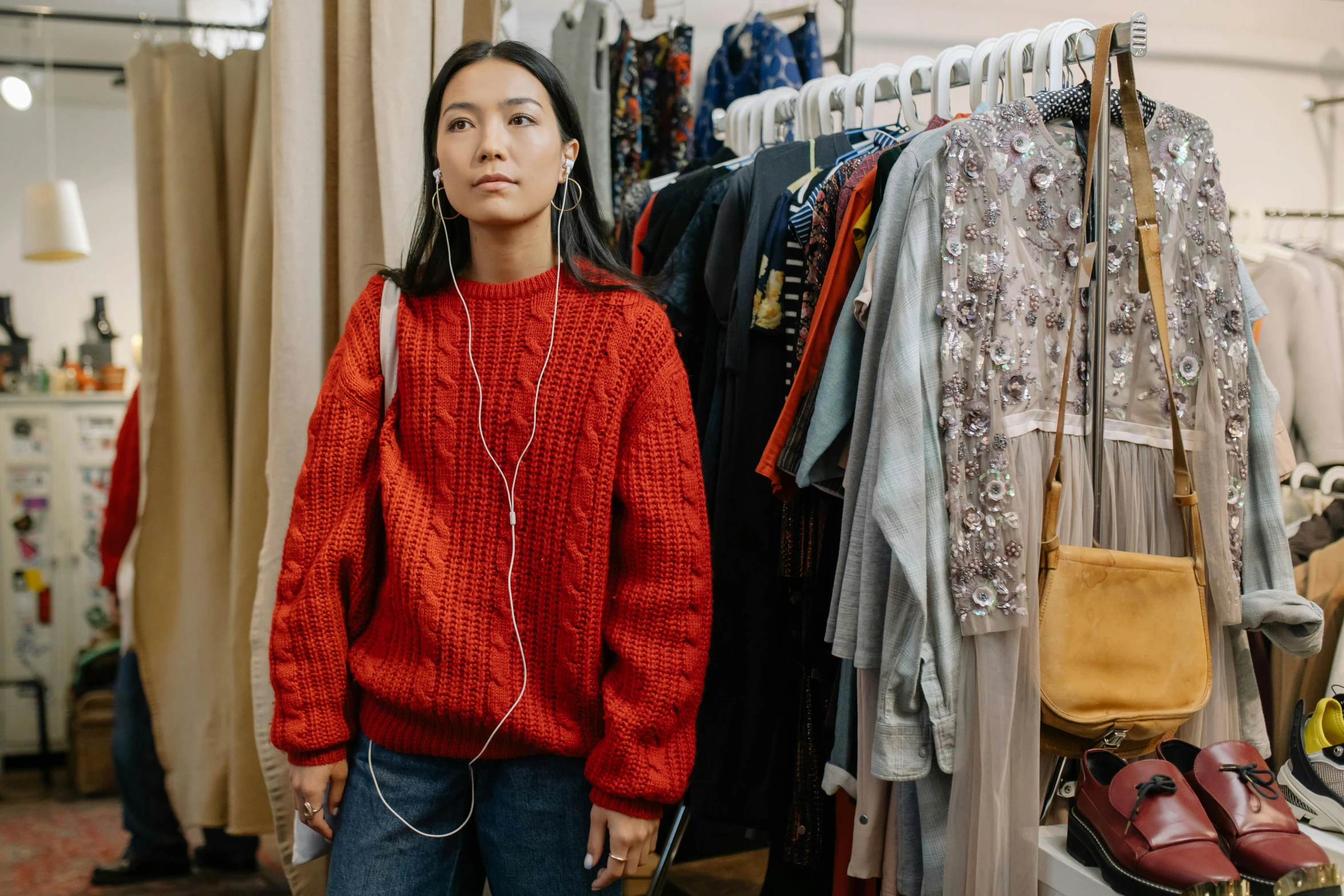 a woman standing in front of a rack of clothes, trending on pexels, maximalism, wearing a red turtleneck sweater, earbuds jewelry, asian female, fashionweek backstage