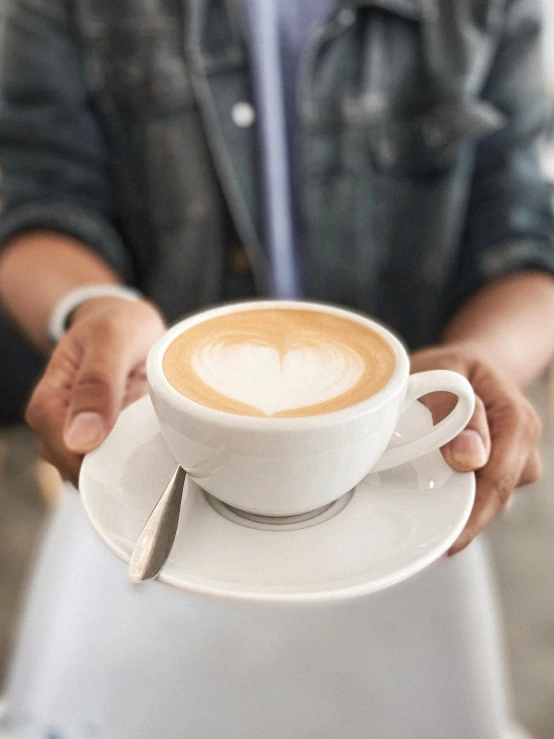 a close up of a person holding a cup of coffee, offering a plate of food, heart-shaped face, latte art, no - text no - logo