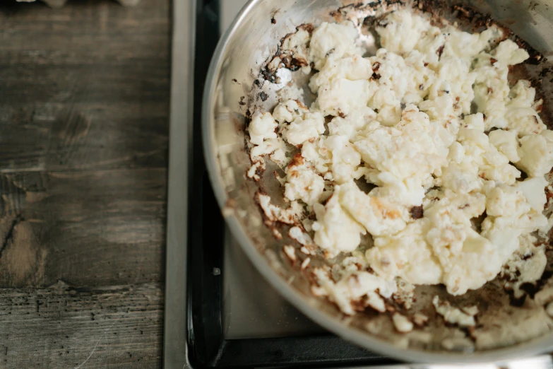 a pan filled with food sitting on top of a stove, by Carey Morris, trending on unsplash, plenty mozzarella, white with chocolate brown spots, al fresco, puffy