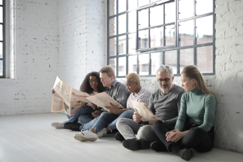 a group of people sitting on the floor reading newspapers, pexels contest winner, private press, diverse ages, profile image, thumbnail, grey
