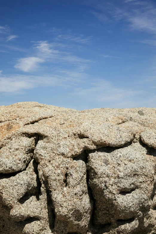 a large rock sitting on top of a sandy beach, rocky roads, granite, rock wall, close ups