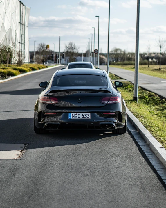 a black car parked on the side of a road, on a road