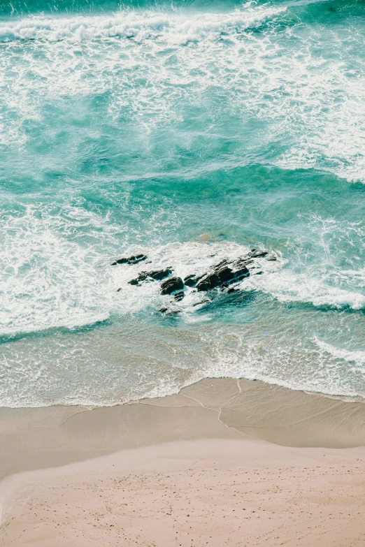 a man standing on top of a sandy beach next to the ocean, pexels contest winner, minimalism, waves crashing at rocks, aerial view top down, south african coast, glistening seafoam