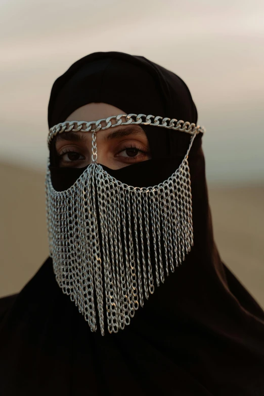 a woman wearing a chain mask in the desert, an album cover, hurufiyya, detail shot, photographed for reuters, veiled face, hila klein