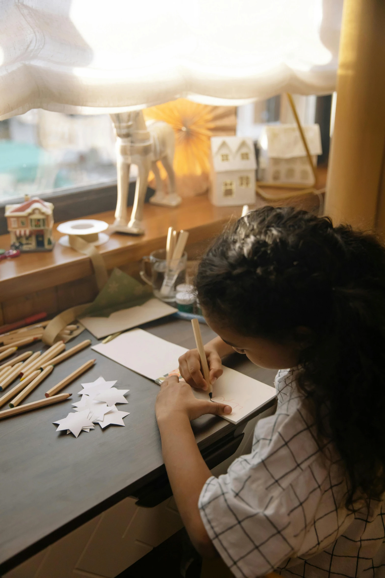 a woman sitting at a desk writing on a piece of paper, a child's drawing, origami studio 3 design, wooden decoration, instagram story, studio kyoto