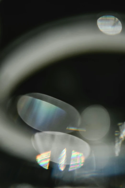 a close up of a camera lens with a blurry background, a microscopic photo, inspired by Bruce Munro, holography, still from film, iridescent smoke, floating metallic objects, grainy footage