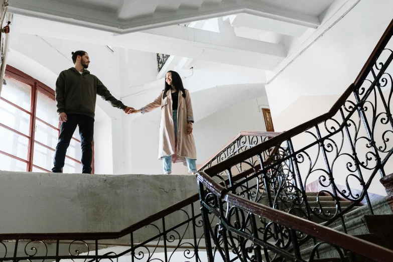 a man and a woman holding hands on a set of stairs, by Lucia Peka, pexels contest winner, ayanamikodon and irakli nadar, location in a apartment, ( ( theatrical ) ), hunting