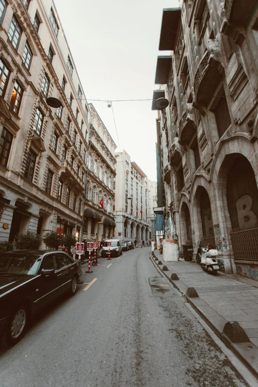 a black car driving down a street next to tall buildings, a picture, pexels contest winner, renaissance, istanbul, narrow and winding cozy streets, gif, vintage photo