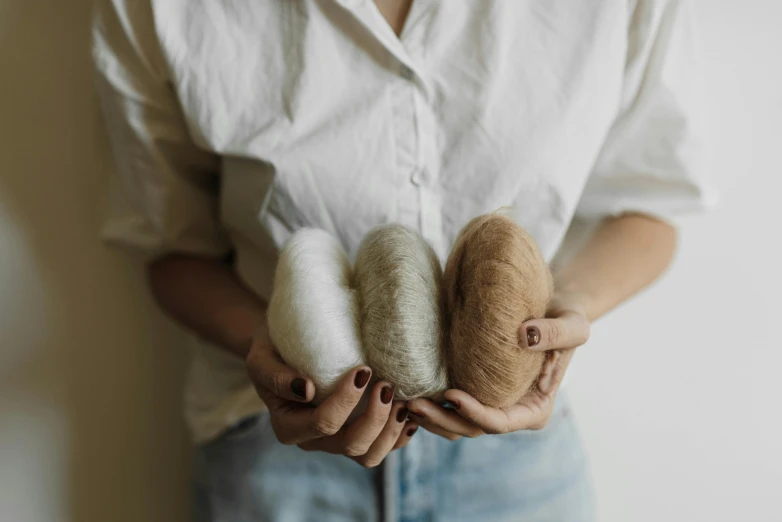 a woman holding two doughnuts in her hands, by Emma Andijewska, trending on unsplash, process art, wool felting art, beige cream natural muted tones, pouches, group photo