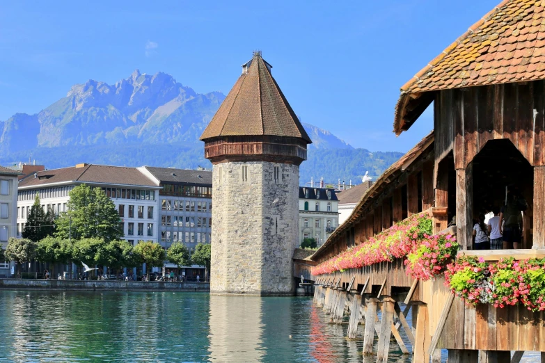 a bridge over a body of water with a clock tower in the background, renaissance, alpine architecture, travel guide, peaked wooden roofs, swiss