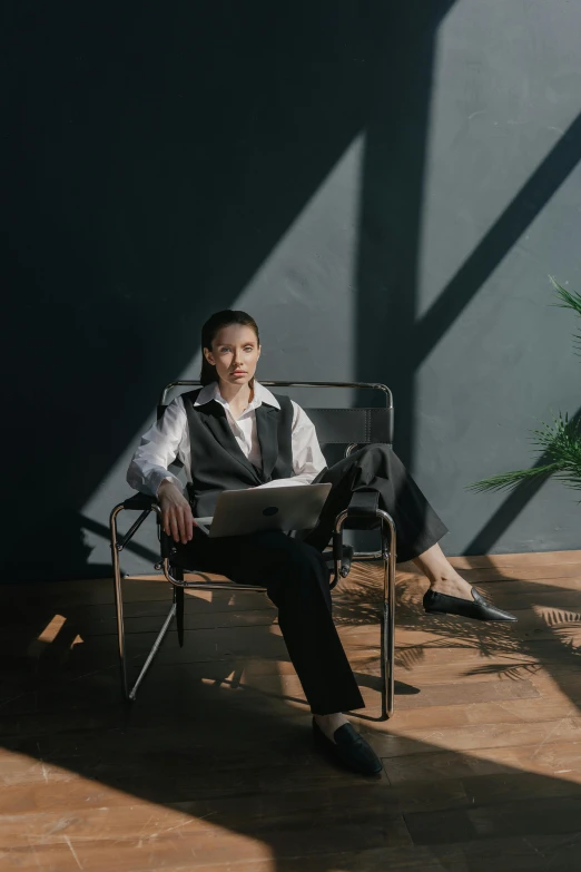 a woman sitting in a chair with a laptop, a portrait, inspired by Fei Danxu, pexels contest winner, androgyny, architect studio, sun lighting, full body picture