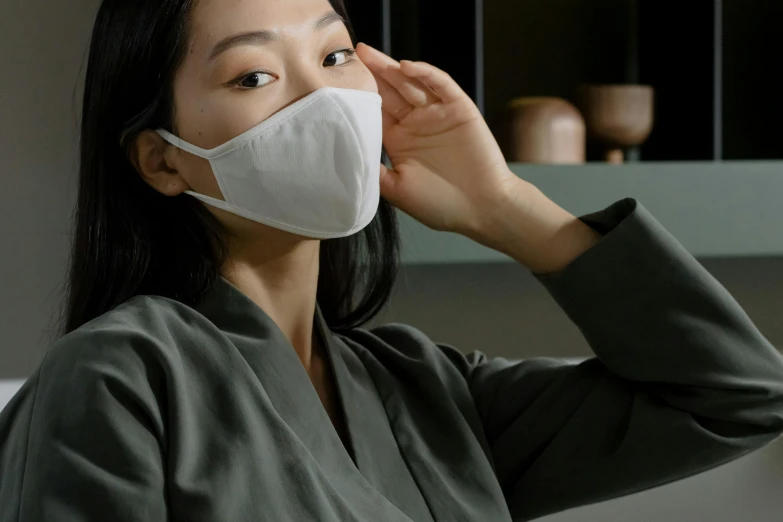 a woman wearing a face mask in a kitchen, inspired by Kanō Naizen, angled, wearing white silk, eora, up-close
