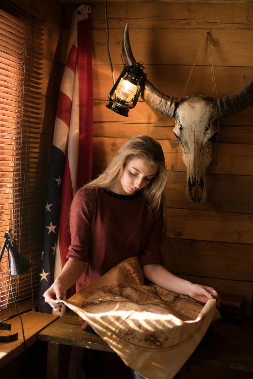 a woman is looking at a map in a cabin, inspired by Terry Redlin, renaissance, cow skull, patriotic, full product shot, student