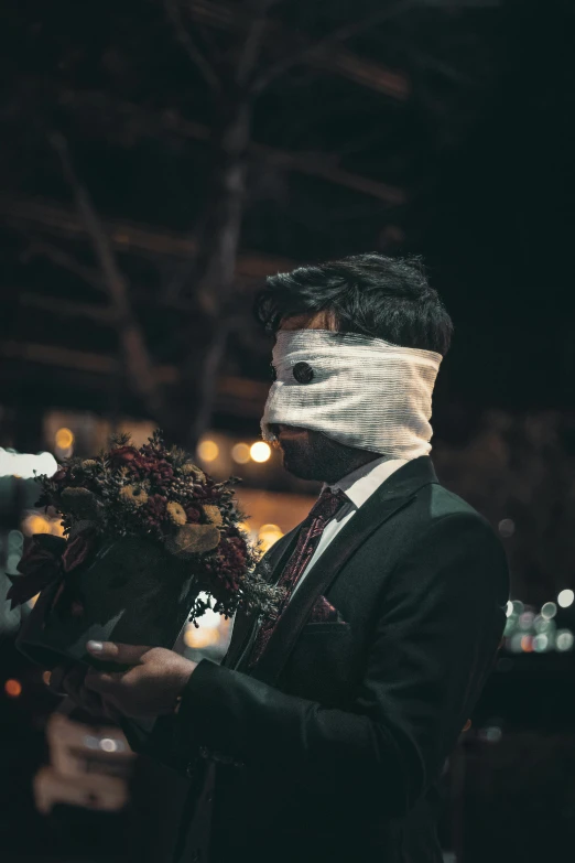 a man in a suit holding a bunch of flowers, an album cover, inspired by Nicola Samori, pexels contest winner, romanticism, carnival mask, discord profile picture, night life, bandaged nose