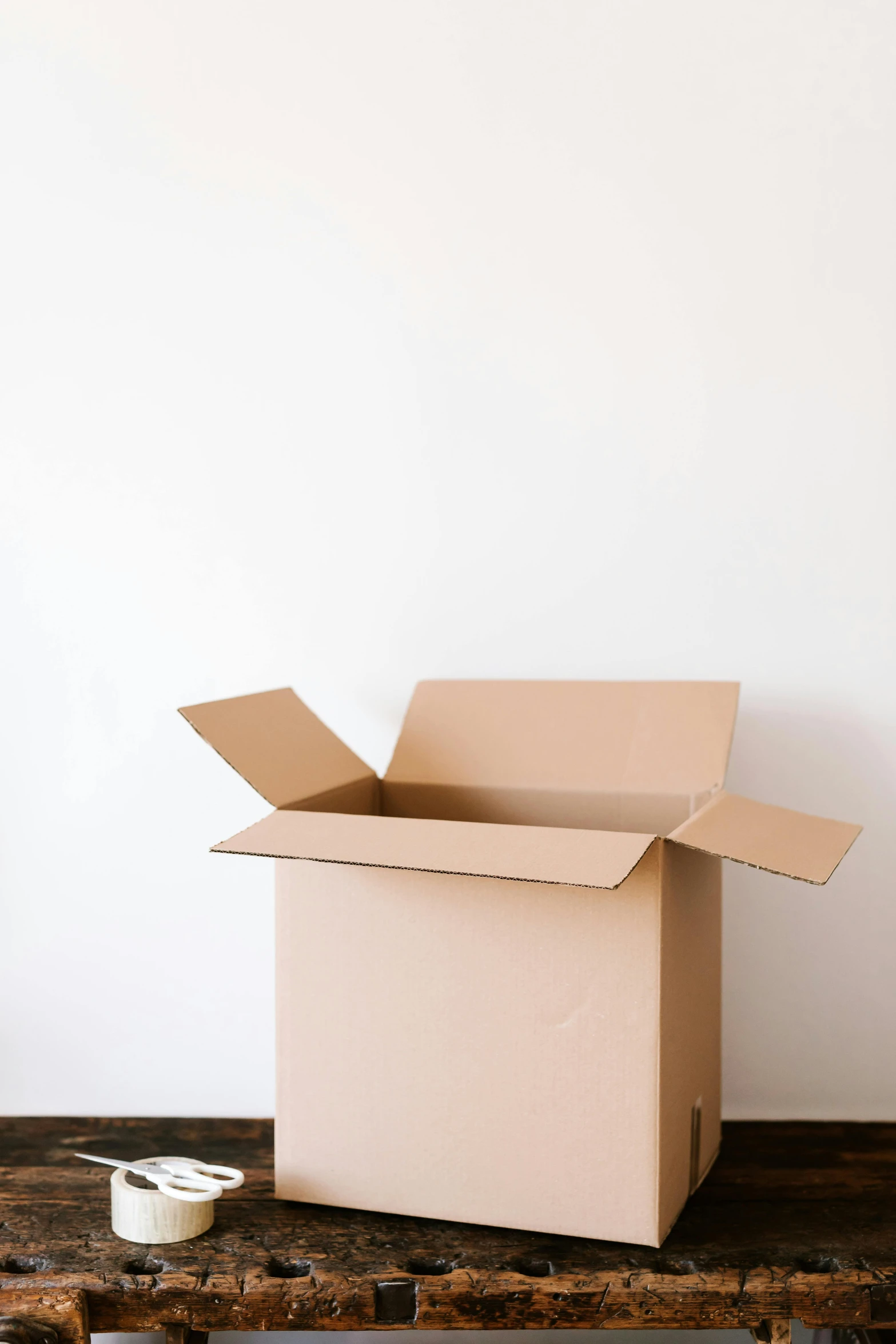 a cardboard box sitting on top of a wooden table, sitting in an empty white room, listing image, kailee mandel, tran ross