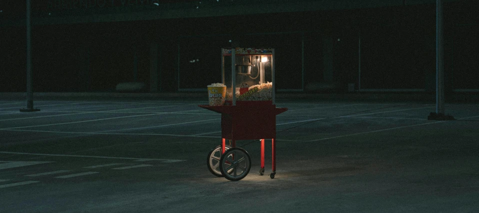 a popcorn cart sitting in the middle of a parking lot, inspired by Elsa Bleda, unsplash contest winner, hyperrealism, people at night, paul barson, horror movie, gumball machine