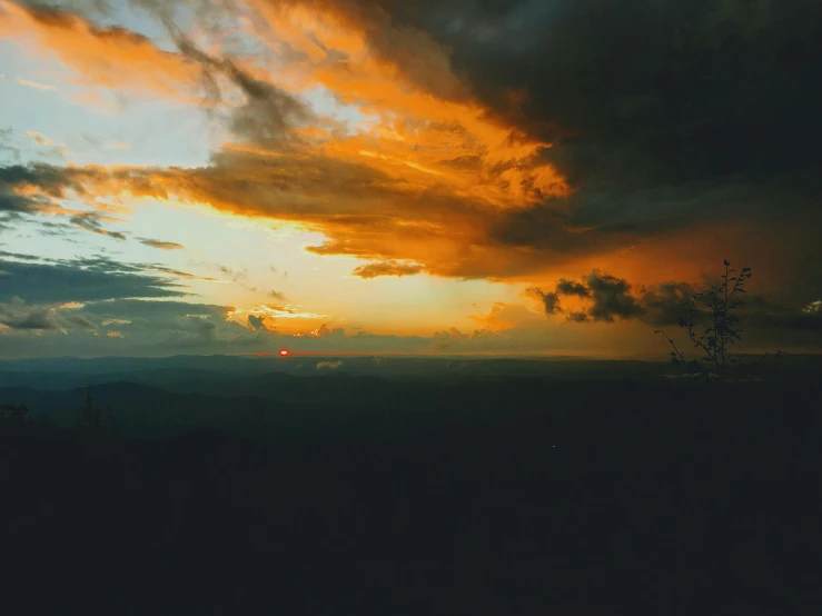 a person standing on top of a hill under a cloudy sky, pexels contest winner, romanticism, orange sun set, dark clouds in the distance, instagram post, patches of yellow sky