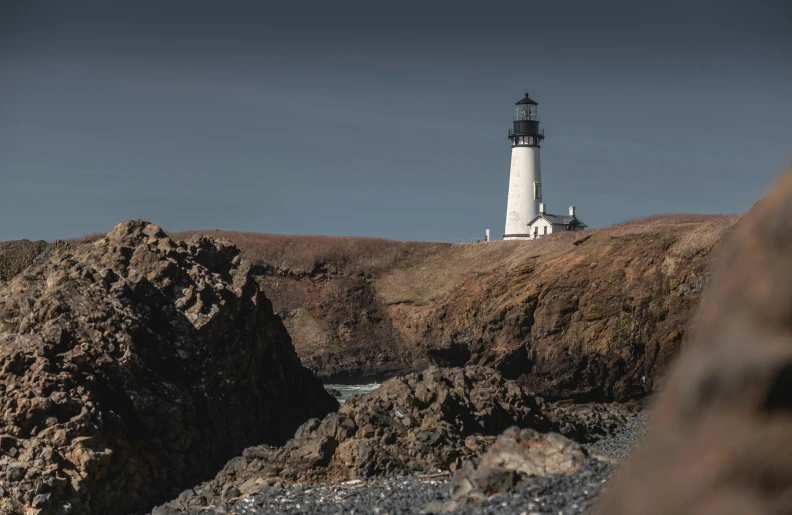 a lighthouse sitting on top of a rocky hill, by Jessie Algie, pexels contest winner, pacific northwest coast, background image, conde nast traveler photo, pembrokeshire