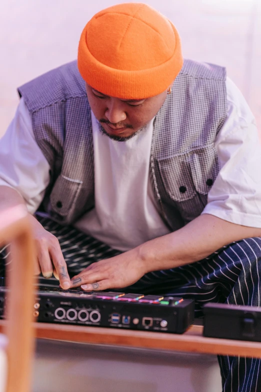 a man in an orange turban working on a laptop, an album cover, inspired by Zhu Da, unsplash, realism, live performance, close up of lain iwakura, electronic music, an instrument