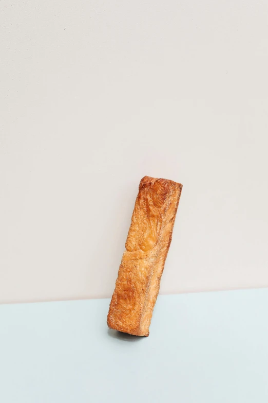 a piece of bread sitting on top of a table, tall thin, pastelle, ignant, product shot