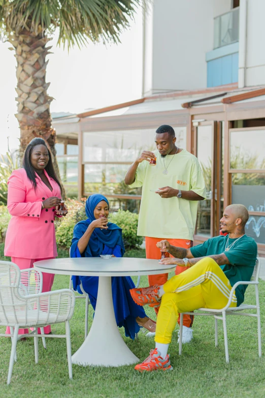 a group of people sitting around a table, by Charly Amani, african ameera al taweel, summer setting, neon colored suit, breakfast