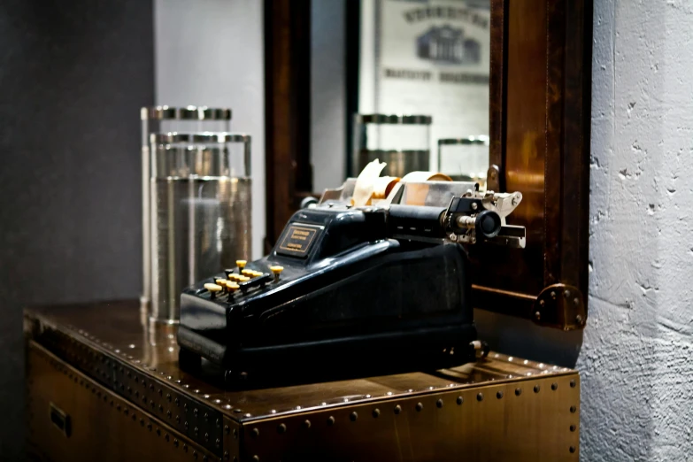 a black typewriter sitting on top of a wooden table, a steampunk store, whiskey, set inside of the bank, futuristic gun