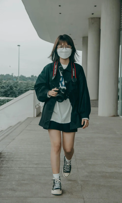 a woman walking down a sidewalk wearing a face mask, inspired by Gang Hui-an, pexels contest winner, girl wearing uniform, 90's photo, taken with canon 5d mk4, casual pose