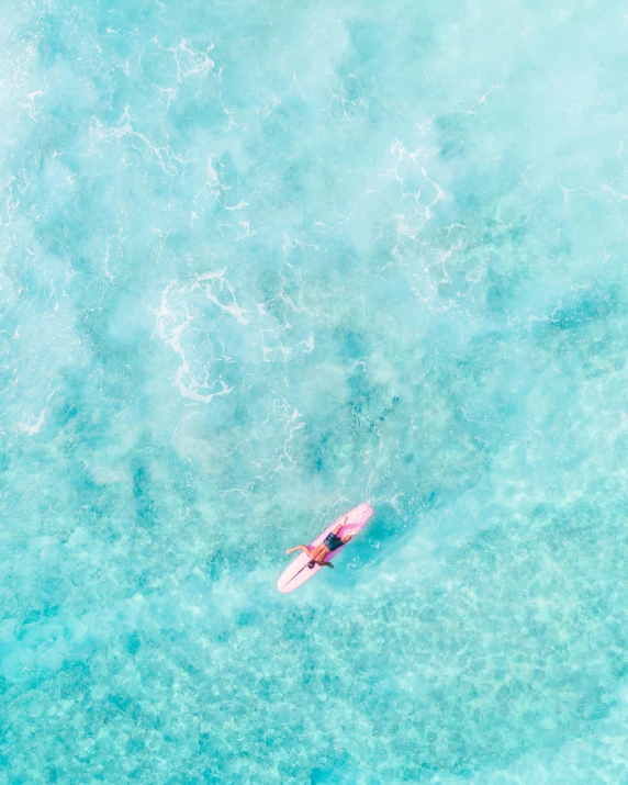 a person laying on a surfboard in the middle of the ocean, pexels contest winner, shades of pink and blue, helicopter view, thumbnail, multiple stories