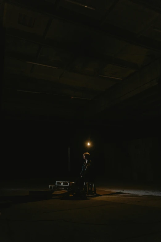 a man riding a motorcycle through a dark tunnel, an album cover, unsplash, light and space, standing on top of a piano, in a dark warehouse, sittin, lonely