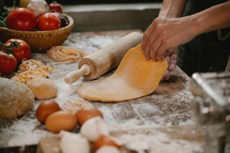 a person rolling out dough on a table, by Julia Pishtar, trending on pexels, fan favorite, wood print, brown, cheesy