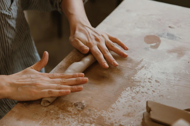 a person rolling out dough on a table, a marble sculpture, inspired by Sarah Lucas, trending on pexels, made of clay, thumbnail, petite, craft