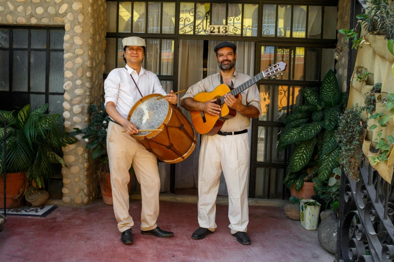 a couple of men standing next to each other holding guitars, inspired by Francisco Zúñiga, delightful surroundings, congas, light tan, promotional photo