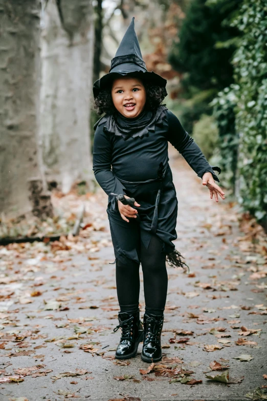 a little girl dressed up in a witch costume, by Nina Hamnett, happening, jet black leggins, black on black, small in size, slay