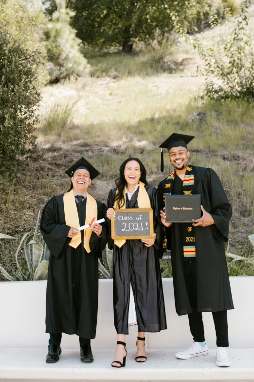 a group of people standing next to each other holding diplomas, unsplash, renaissance, trees in background, gold and black color scheme, cardboard cutout, bay area