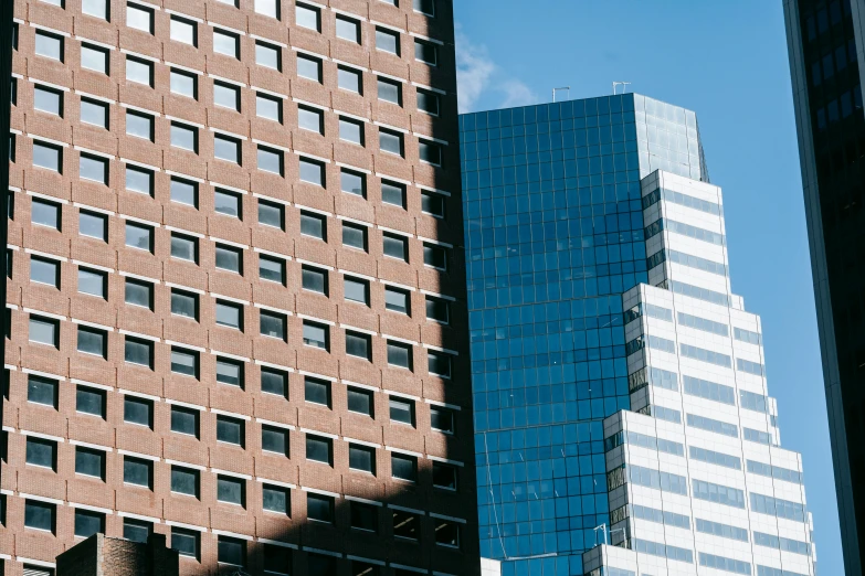 a couple of tall buildings sitting next to each other, a photo, unsplash, modernism, brown, aquamarine windows, corporate, brick building