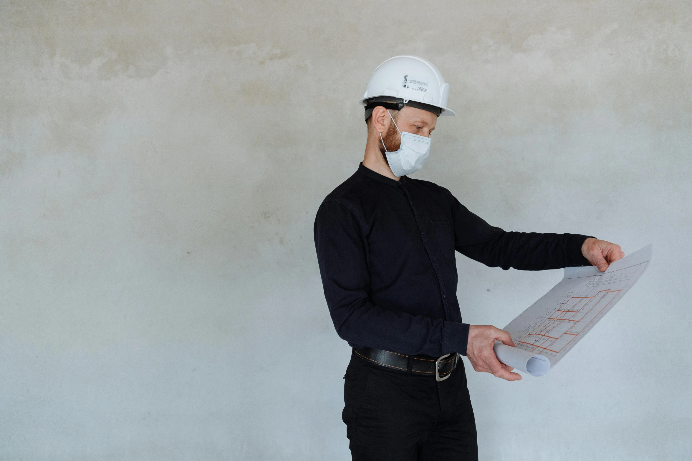 a man wearing a face mask and holding a blueprint, by Carey Morris, pexels contest winner, white concrete, looking from side, lachlan bailey, helmet