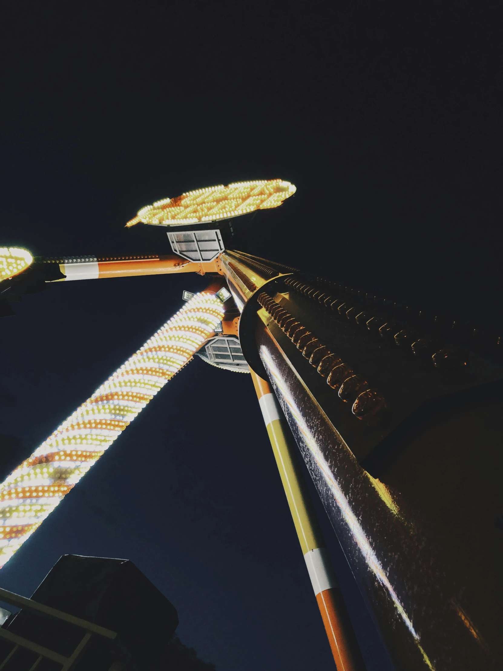 a close up of a carnival ride at night, unsplash contest winner, photorealism, 3/4 view from below, long necks, golden towers, trending on vsco