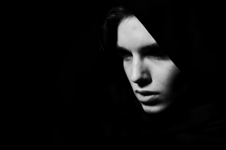 a black and white photo of a woman's face, a black and white photo, by Karl Buesgen, young shadow mage male, wearing a black hoodie, dark drapery, teen boy