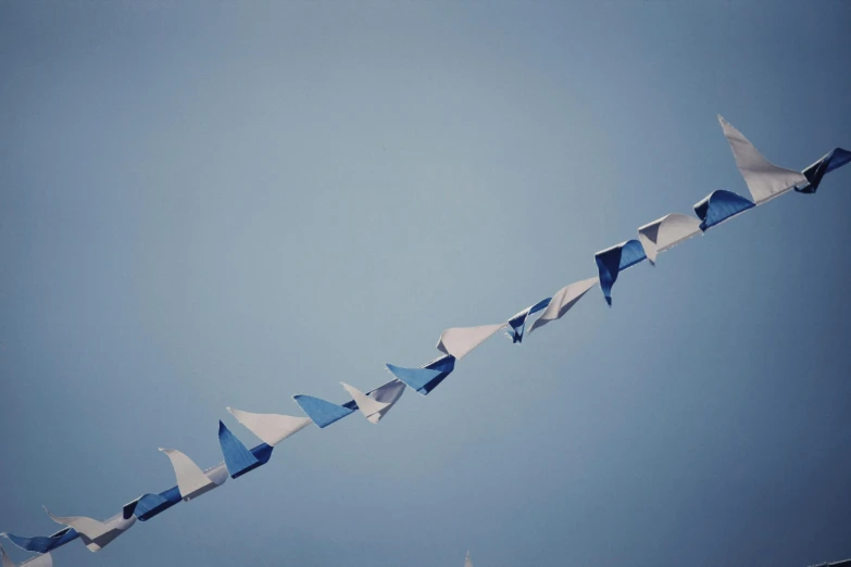 a blue and white kite flying through a blue sky, by Jessie Algie, postminimalism, gang flags, archival pigment print, ((blue)), parade