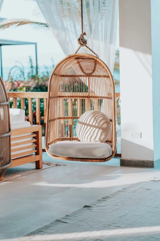 a couple of chairs sitting on top of a porch, made of bamboo, hanging, poolside, indoor setting