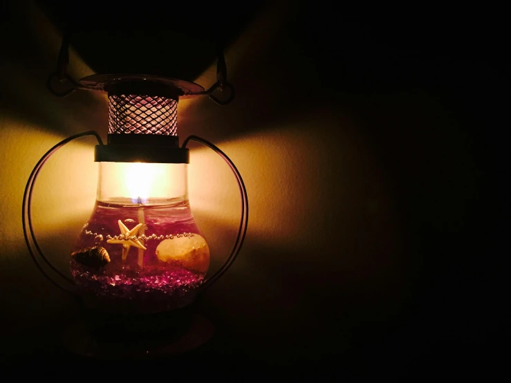 a candle that is lit up in the dark, pink and purple, lantern, lamp ( ( ( fish tank ) ) ) ), indoor picture