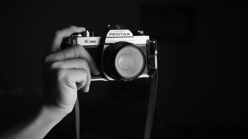 a black and white photo of a person holding a camera, pixabay contest winner, 8 0 s camera, pentax k-1000, photographic print, photograph ”