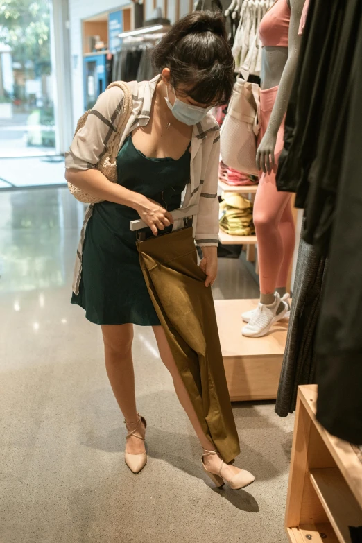 a woman wearing a face mask and holding an umbrella, instagram, happening, put on a mannequin, wearing a tanktop and skirt, green and brown clothes, california;