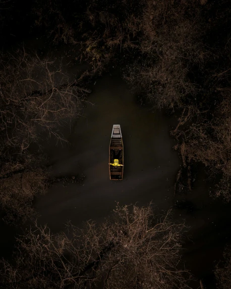 a boat floating on top of a body of water, by Adam Marczyński, pexels contest winner, conceptual art, in dark woods, yellow and black color scheme, looking down on the camera, dark. no text