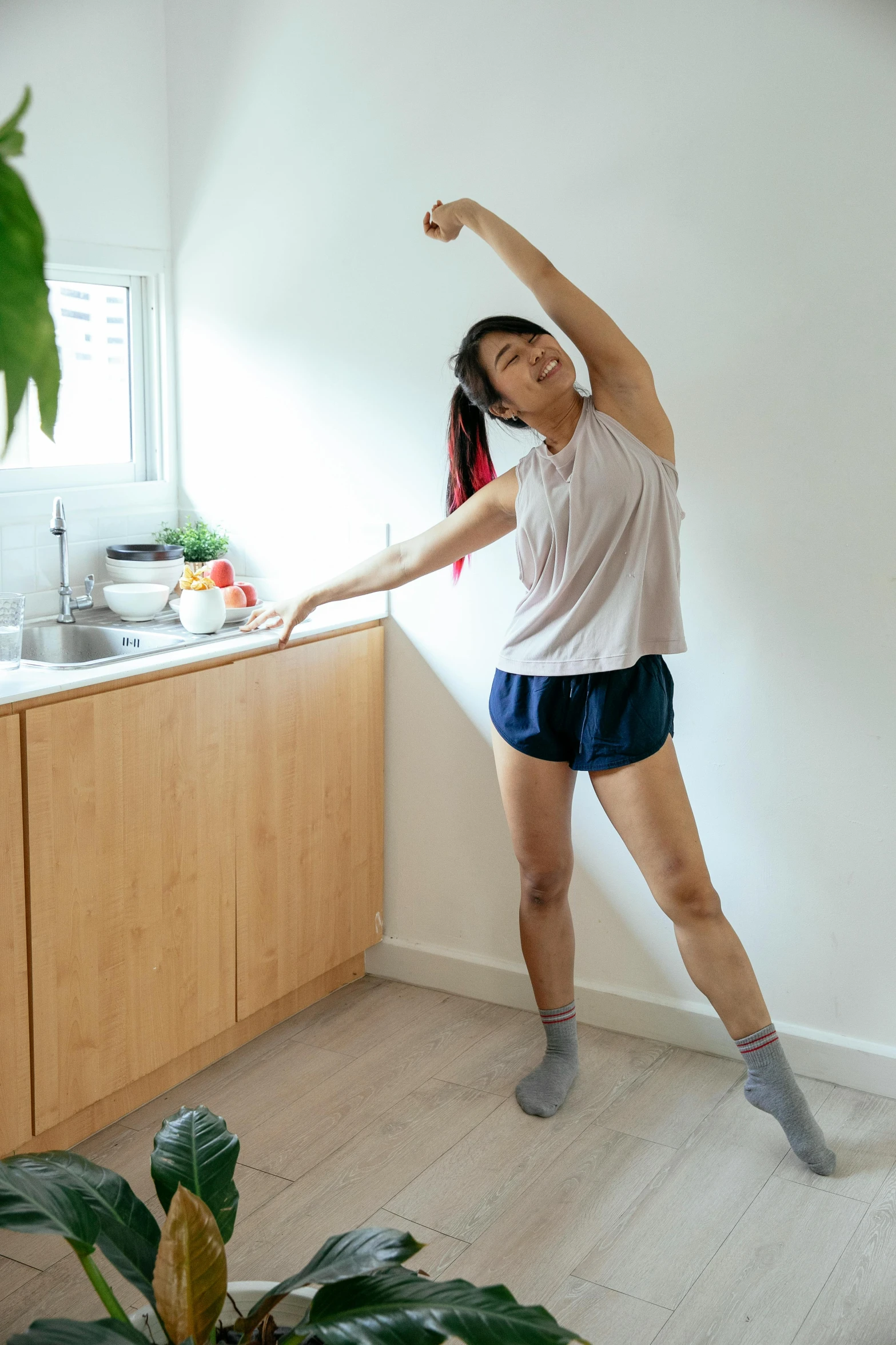 a woman standing in a kitchen with her arms in the air, happening, dynamic stretching, jakarta, wearing shorts and t shirt, maintenance