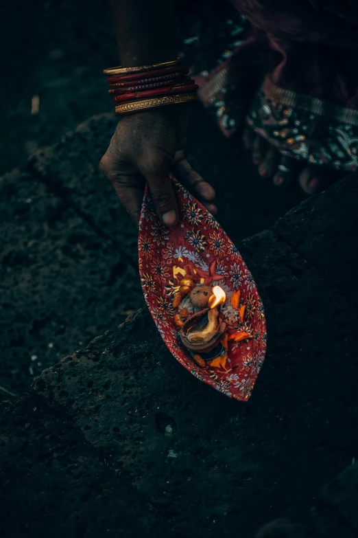 a close up of a person holding a plate with food on it, an album cover, by Elsa Bleda, pexels contest winner, symbolism, torches in ground, hindu gods, paisley, ashes
