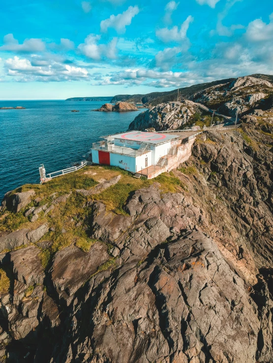 a house sitting on top of a cliff next to the ocean, helipad, profile image, drone photo, norwegian landscape