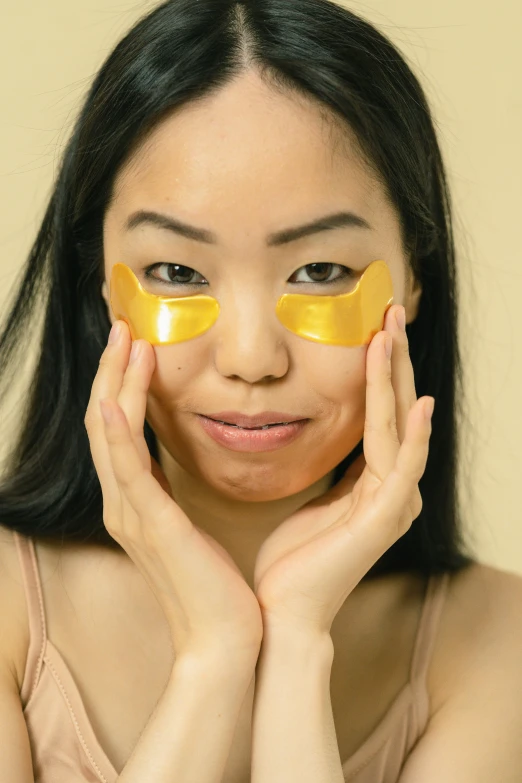 a woman with a yellow eye patch on her face, japanese collection product, full of golden layers, partially cupping her hands, wavy